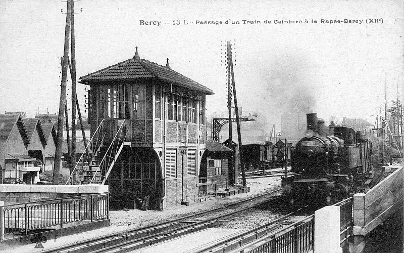Un train de la Petite Ceinture arrive à la station La Rapée-Bercy et va passer au-dessus des voies de la gare de Paris-Lyon vers 1910 